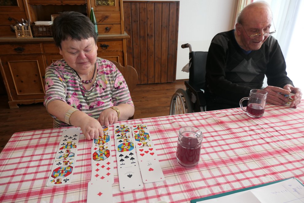 Frau und Mann sitzen mit Karten bei Tisch