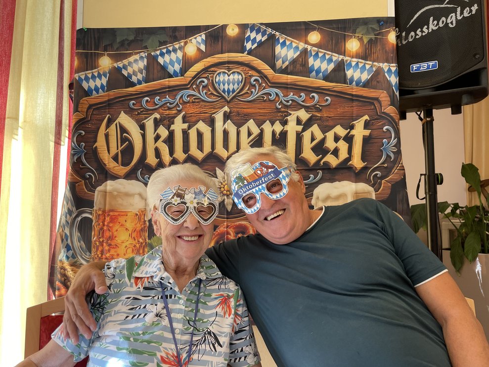 Zwei Personen lächeln mit Oktoberfest Brillen in die Kamera.