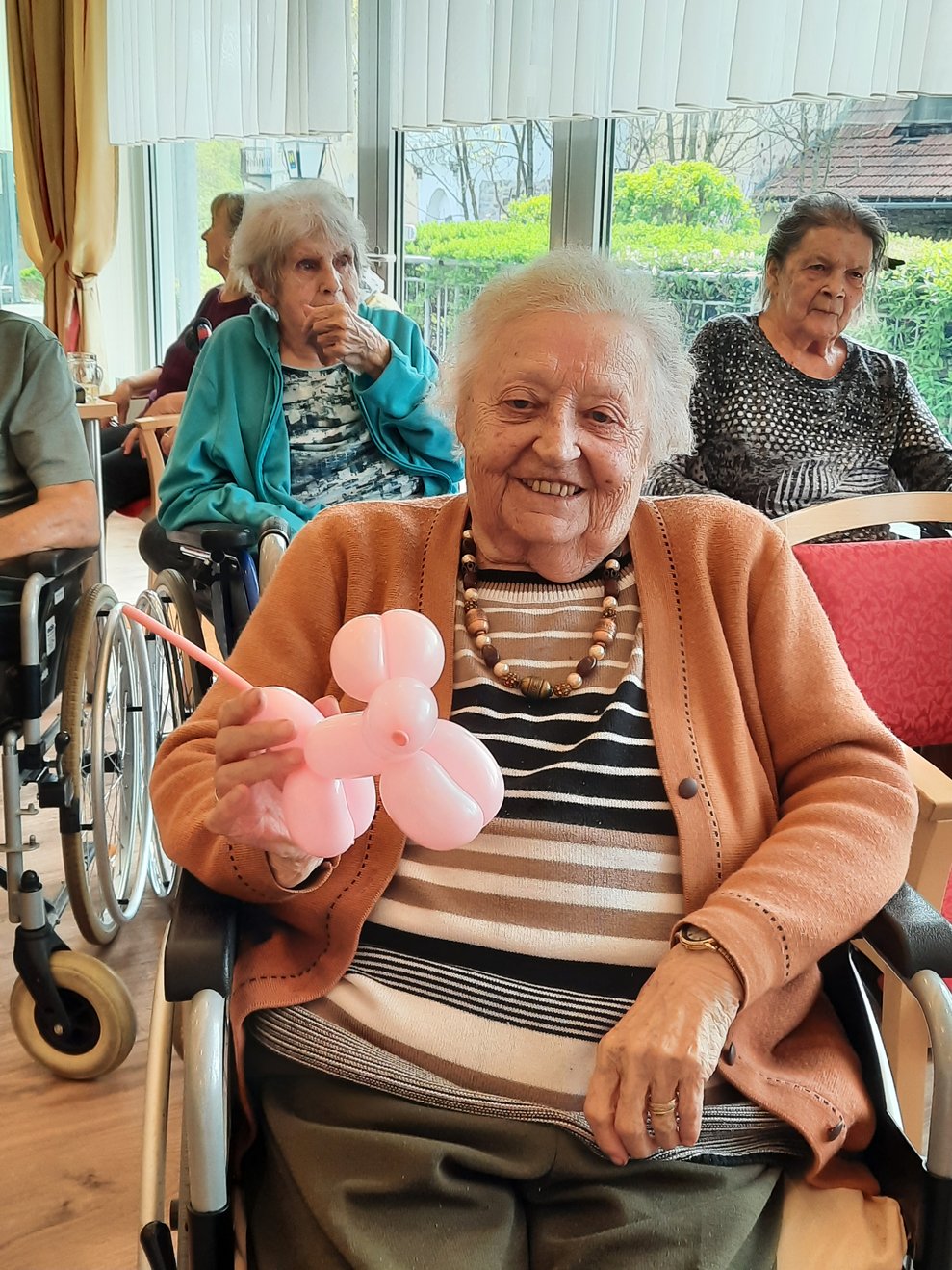 Eine Dame hält ein rosa Luftballontier in die Kamera.