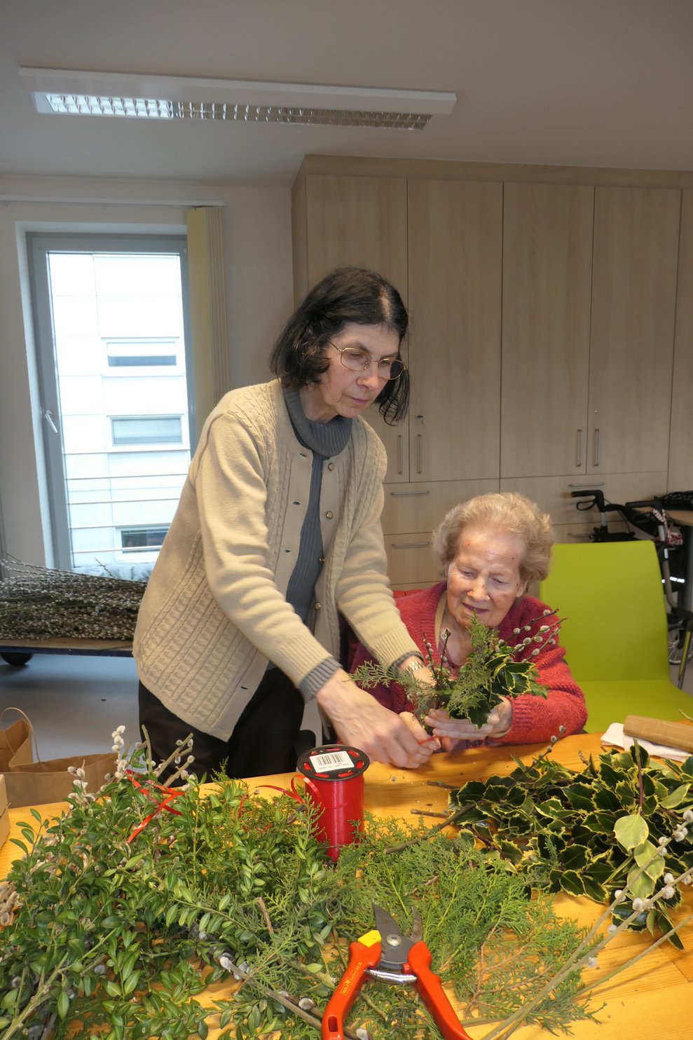 Bewohnerin und Ehrenamtliche beim Palmbuschen binden