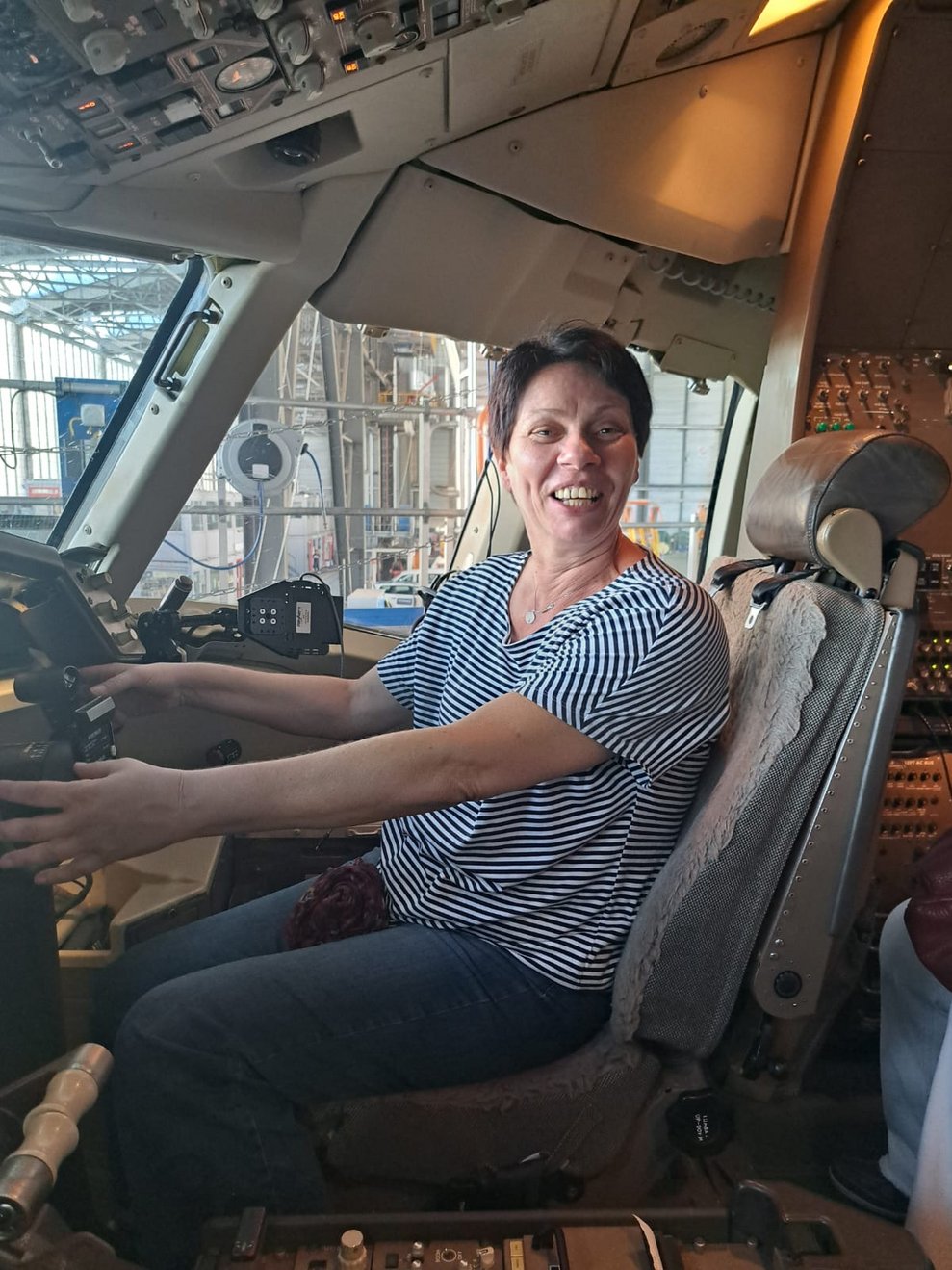 Frau sitzt im Cockpit und hält das Steuerhorn