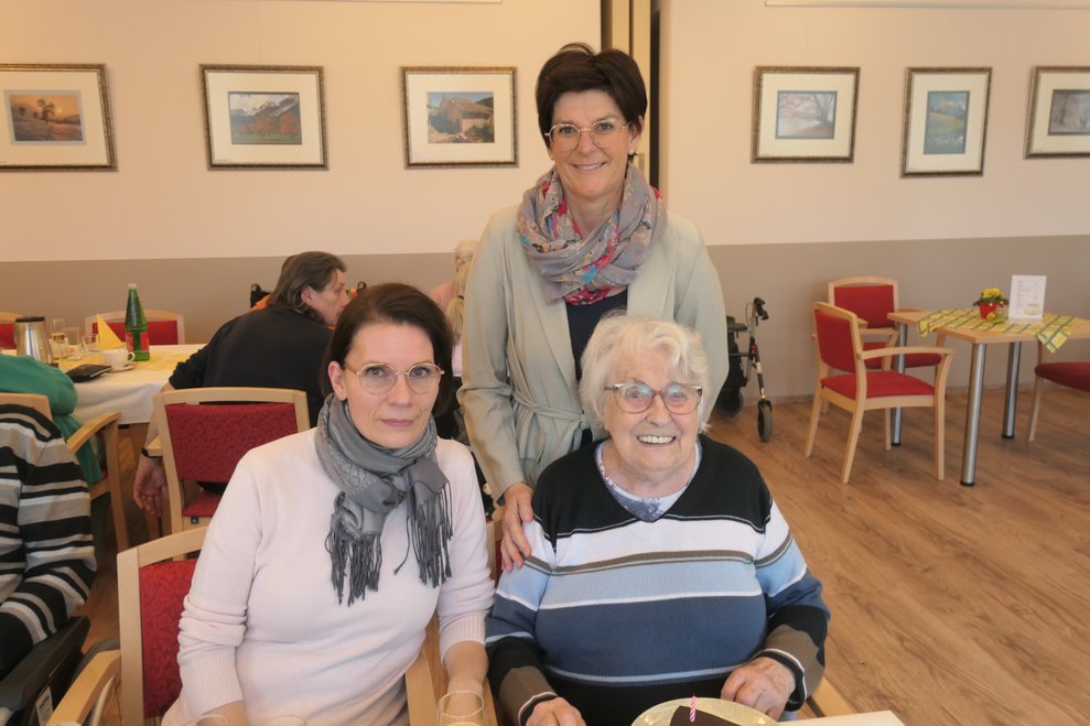 Drei Personen lächeln in die Kamera.